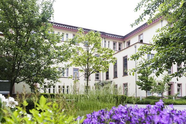 Die Außenanlage des Altenheimes Am Pixbusch II mit Blumen im Vordergrund, weißes Gebäude im Hintergrund