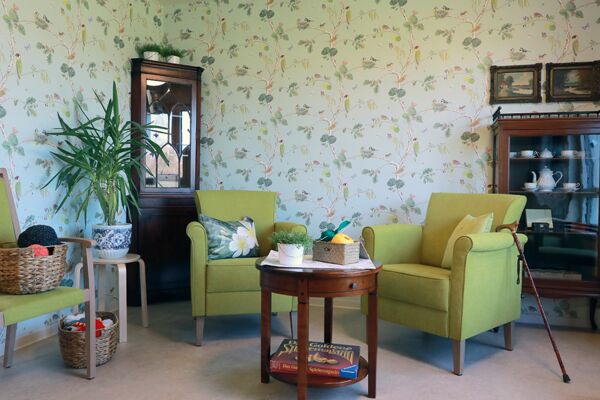 Aufenthaltsbereich im Altenheim Hardterbroich mit grünen Sesseln, Blumentapete und Beistelltischen