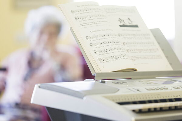 Gemeinsames musizieren im Altenheim Am Pixbusch 1, sie sehen ein E-Piano und Noten